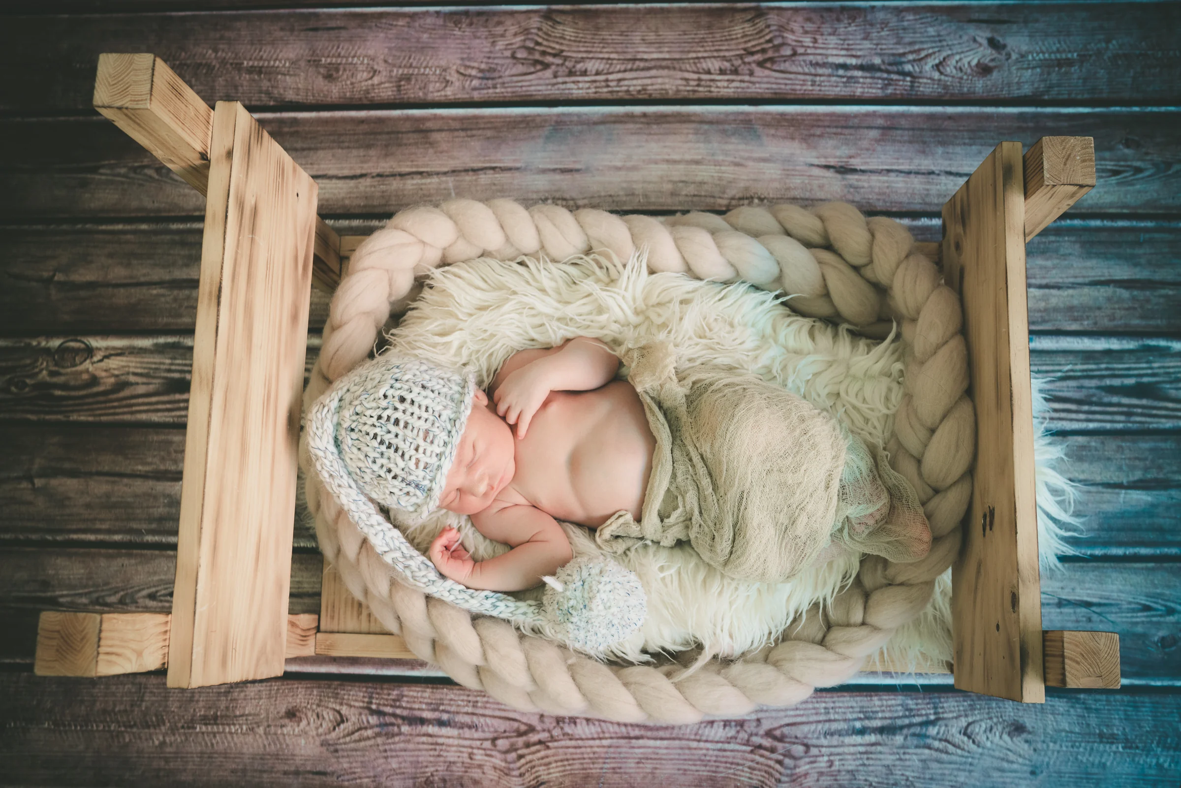 Recién nacido dormido de lado en una caja de madera durante la sesión newborn.