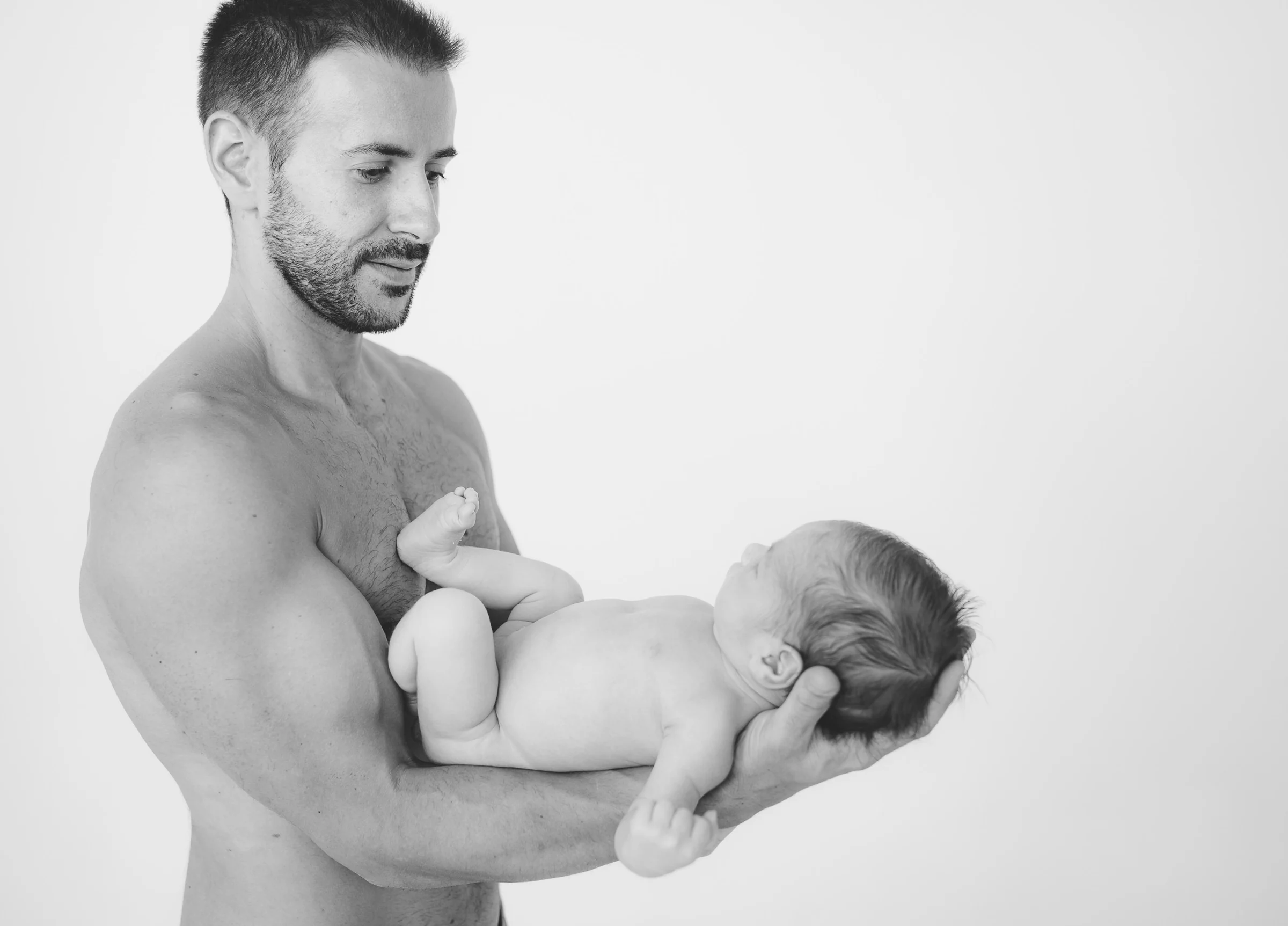Retrato en blanco y negro de un padre sosteniendo a su recién nacido.