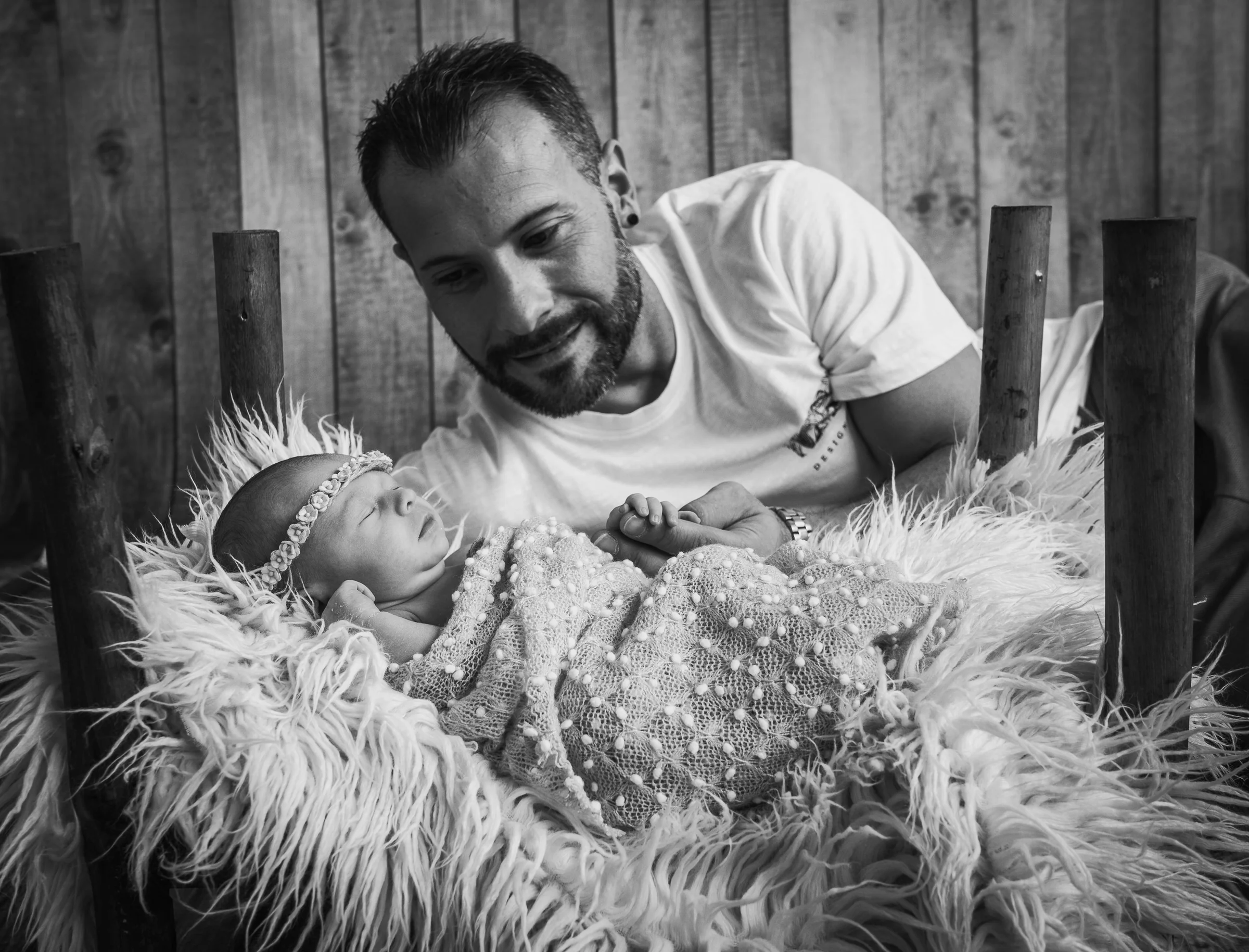 Padre observa al recién nacido en una imagen en blanco y negro de estudio.
