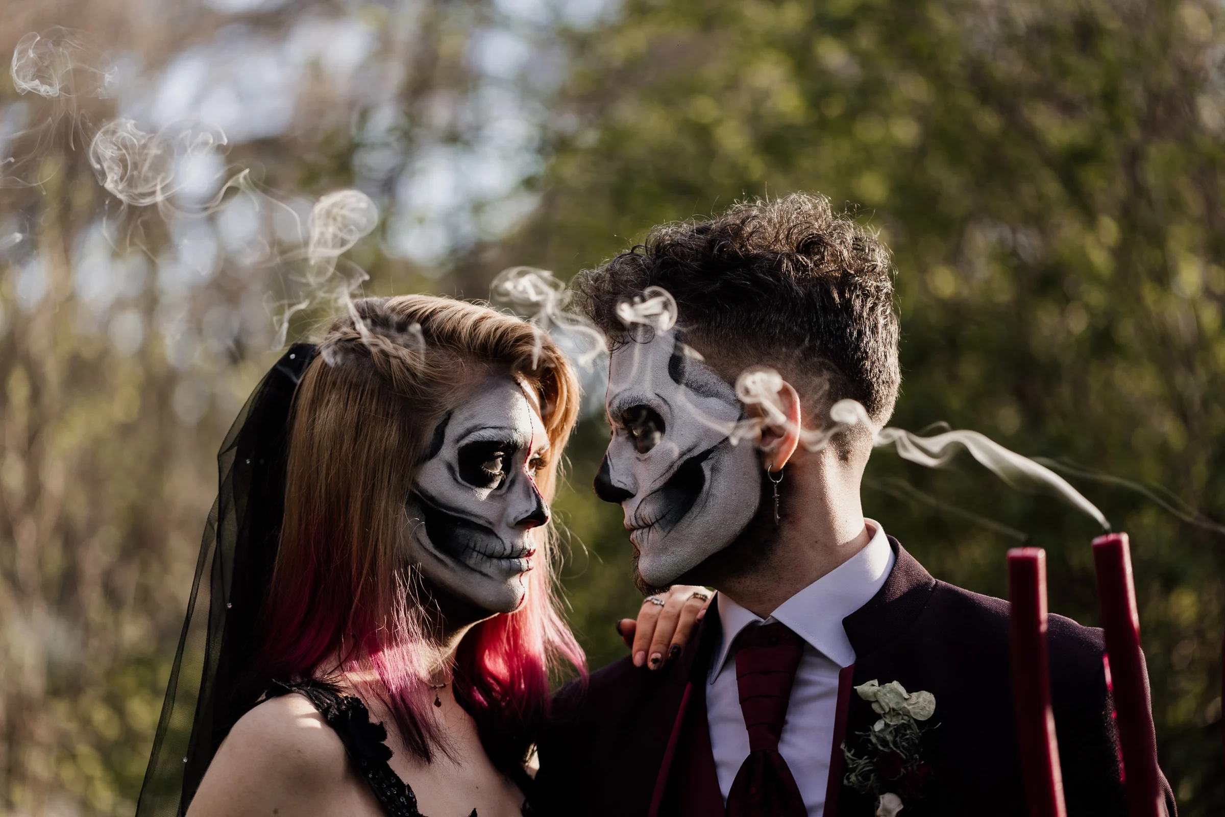 Silvia y Rubén se miran de cerca entre humo y velas rojas durante su postboda gótica en el Parque de El Retiro.