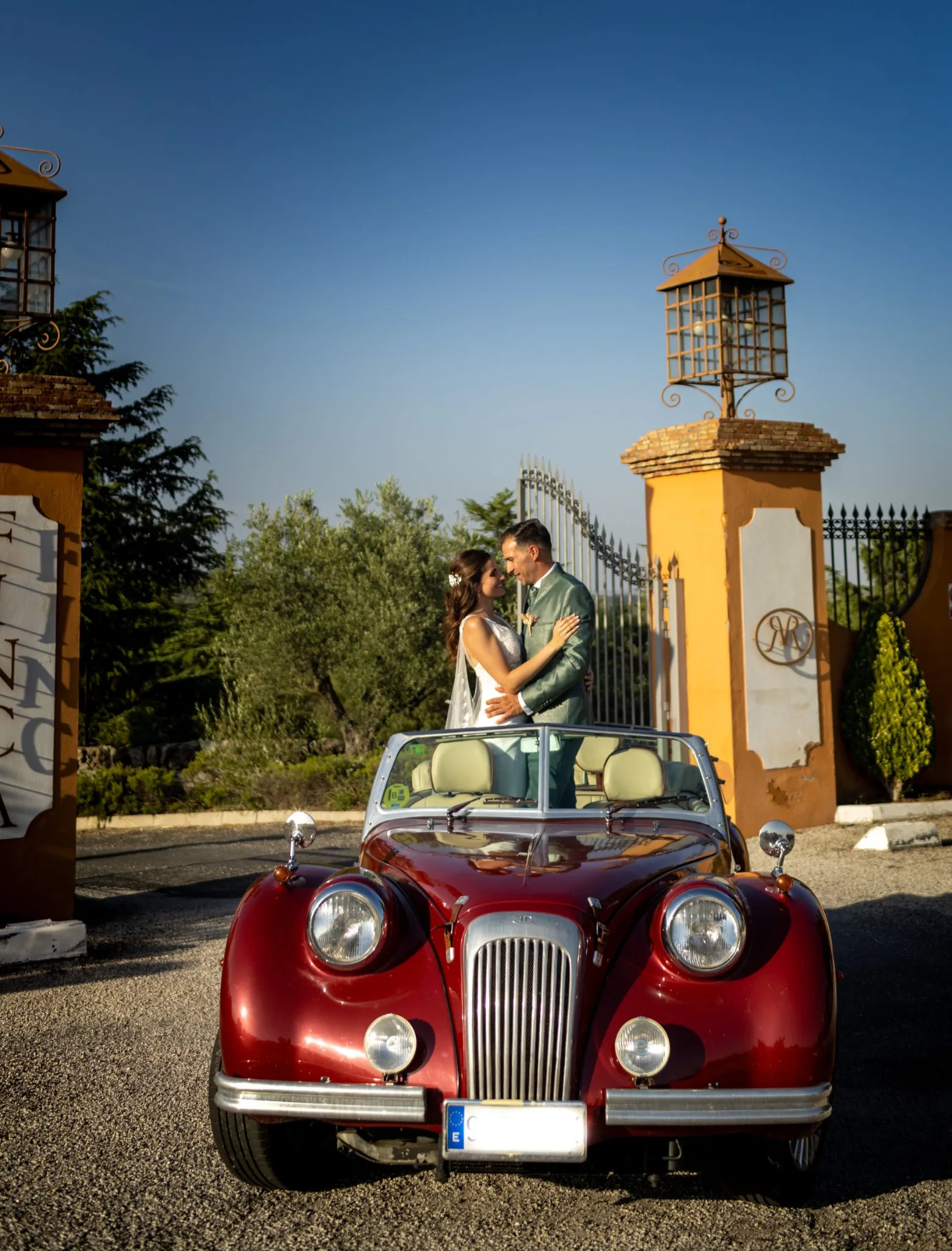 Novios posando con coche clasico rojo durante una boda en Valquijancho.