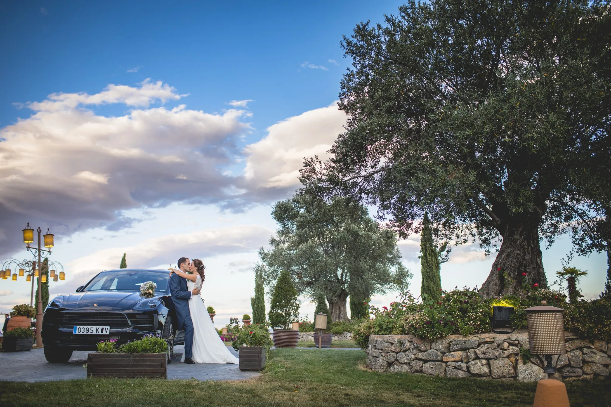 Novios junto al coche en los jardines durante una boda en Valquijancho.