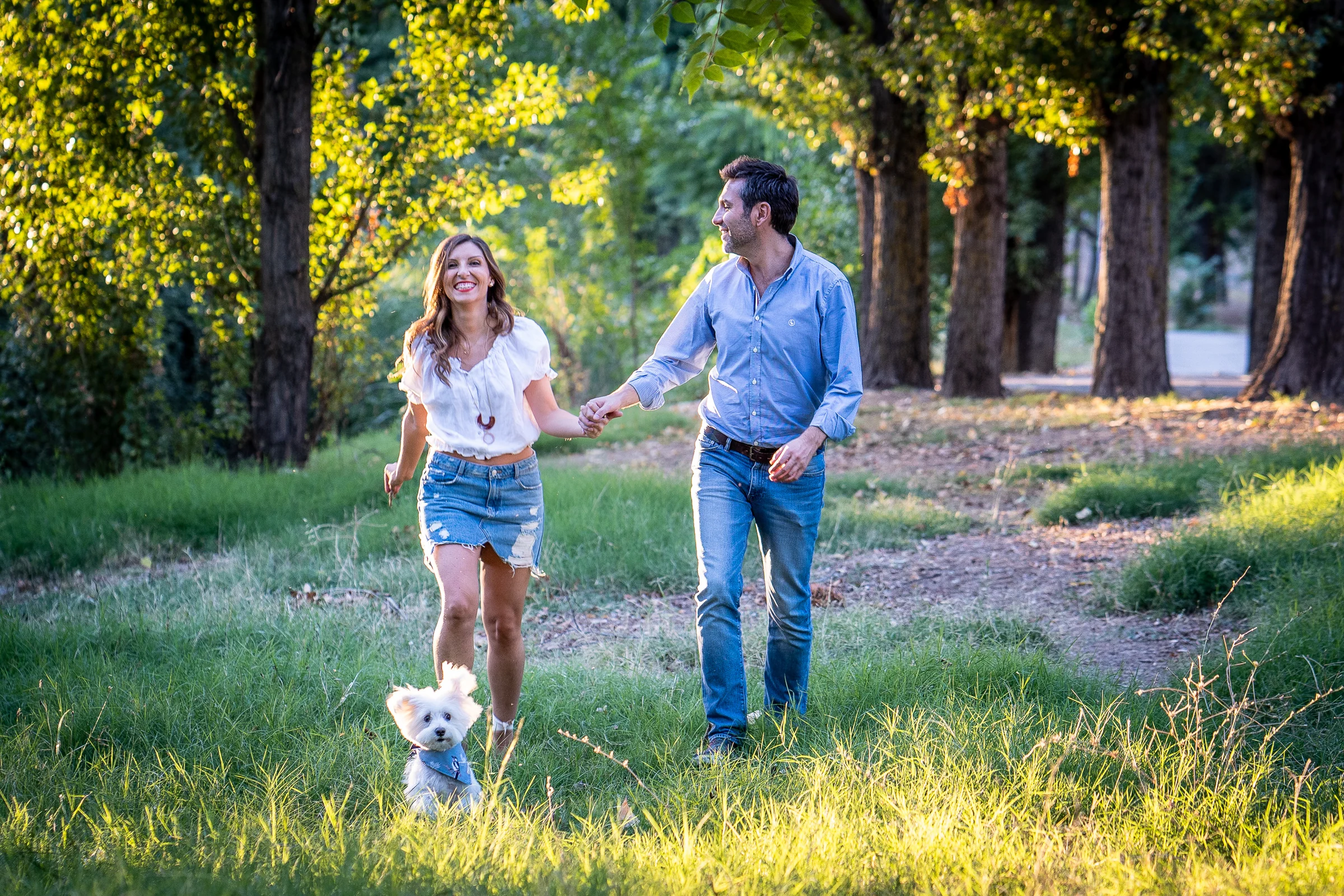 Vanesa y Fran caminan juntos por el parque con su perro durante la hora dorada de su preboda en Madrid.